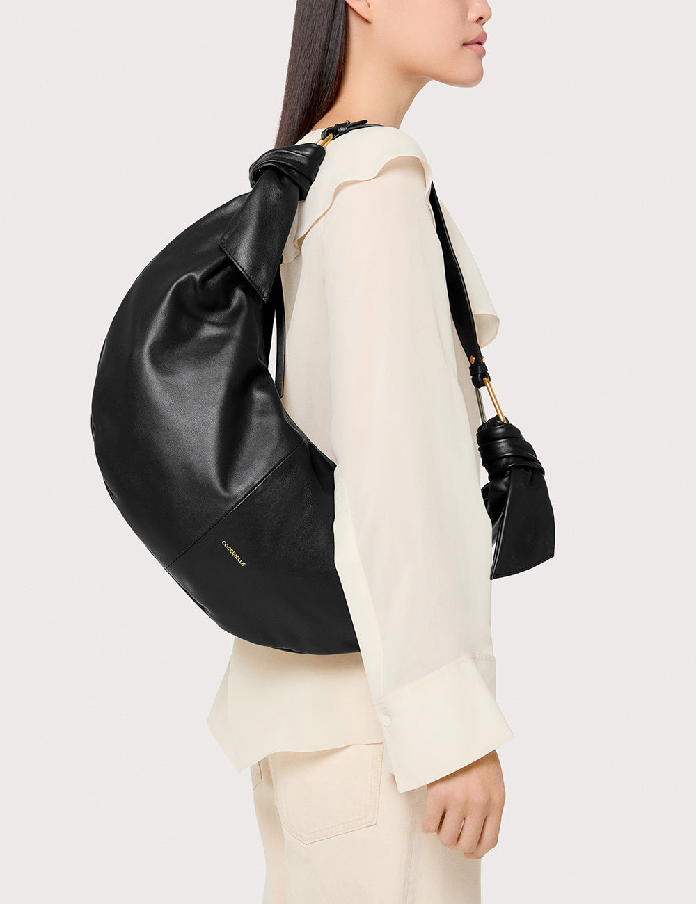 Zaino Coccinelle Furoshiki Large Noir in pelle nera con design curvo e dettagli oro