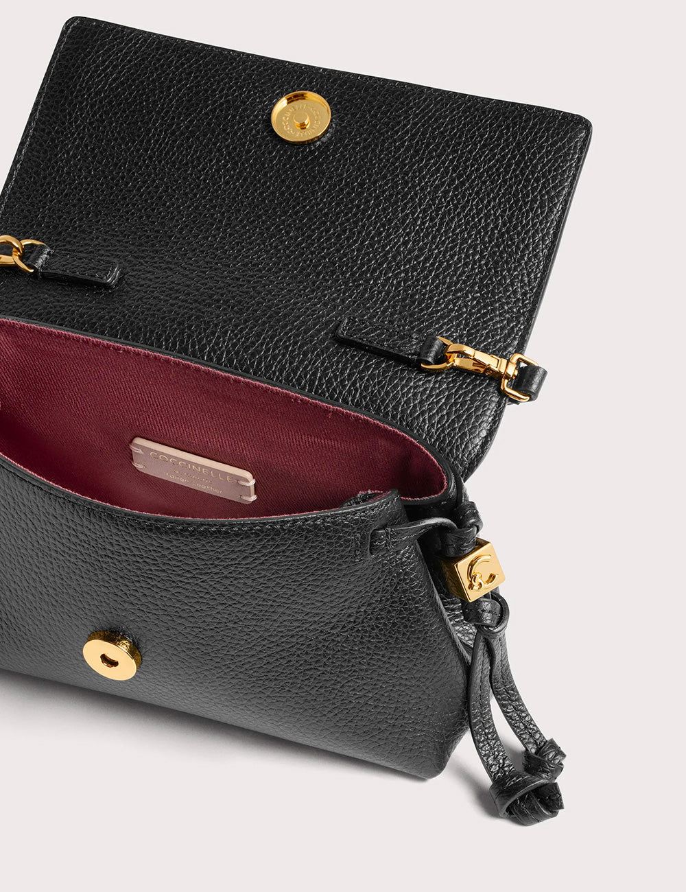 Borsa a tracolla coccinelle thess mini noir in pelle nera martellata con dettagli oro e interno bordeaux