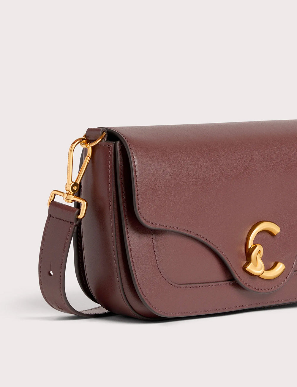 Borsa tracolla coccinelle c-me medium berry in pelle bordeaux con chiusura c intrecciata oro e dettagli in metallo oro